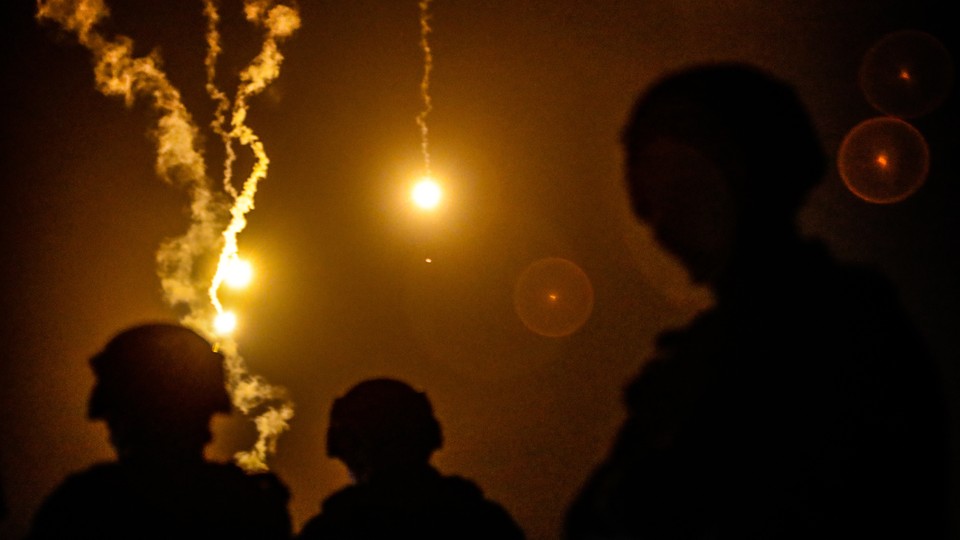 Taiwanese soldiers silhouetted against flares in the night sky
