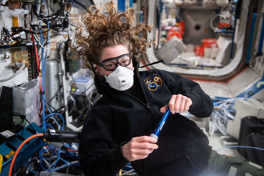 An astronaut's long hair floats above their head as they work aboard the International Space Station.