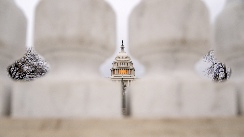 A view of the Capitol building from afar between pillars