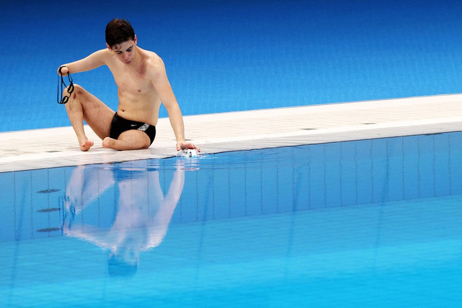A swimmer sits at the edge of a pool.