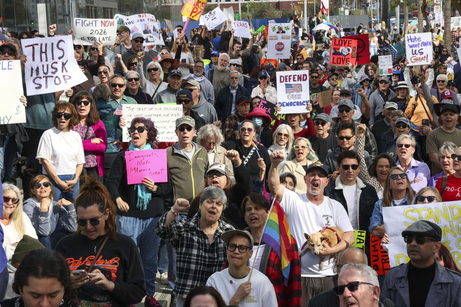 A crowd of protesters hold up signs, including ones that read 