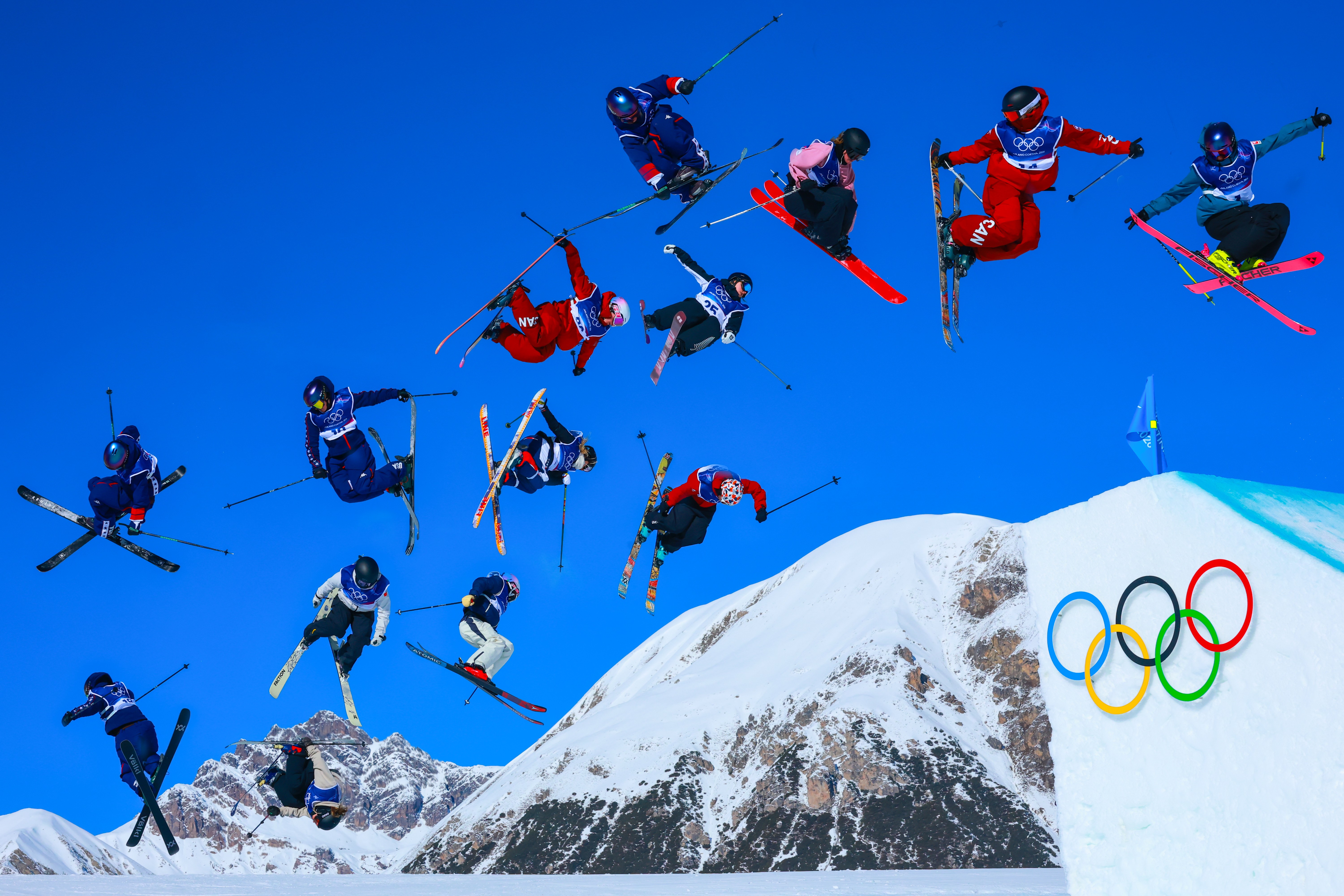 A composite view of fourteen different skiers in mid-air, making it appear as if they had all jumped at nearly the same moment.
