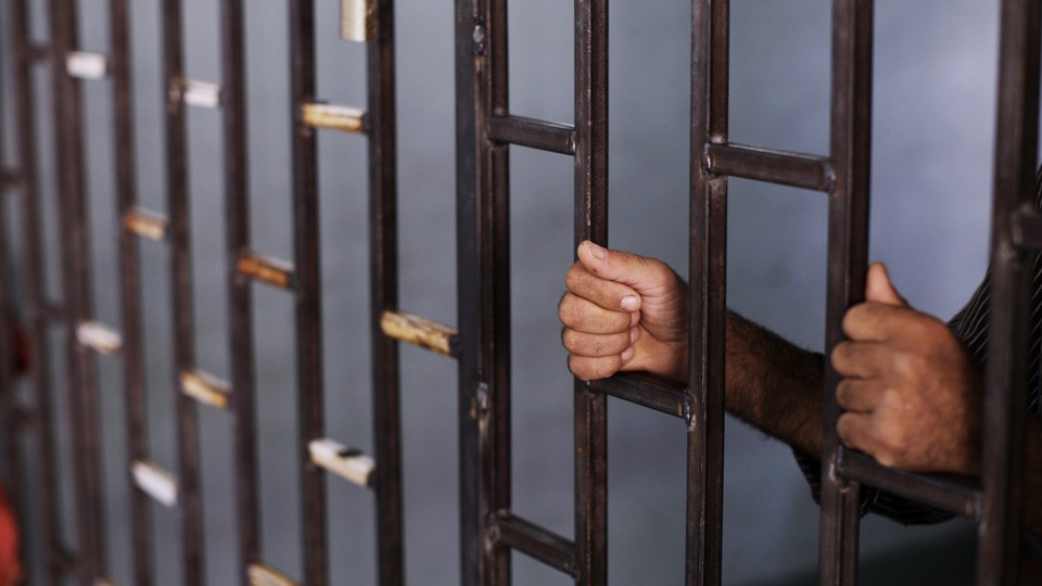 A Syrian prisoner holds the bars of a makeshift prison.