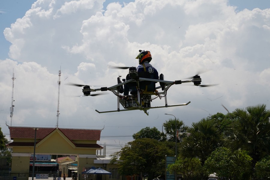 A student flies in a large drone several feet off the ground.