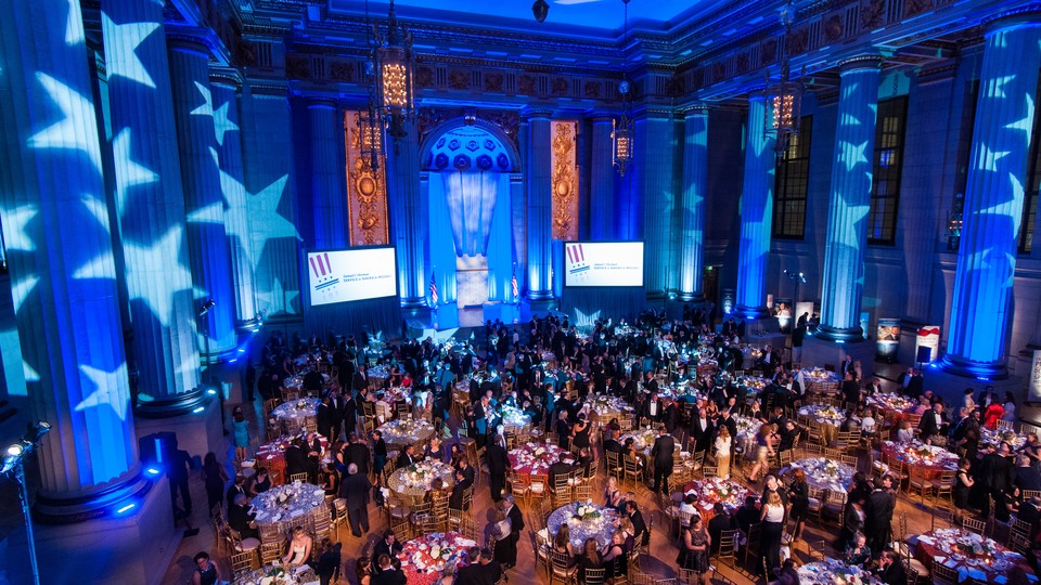 Large blue event hall filled with tables of guests