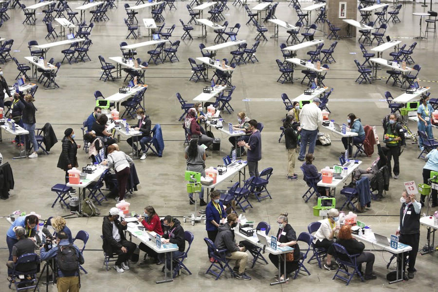 Dozens of people sit at tables arranged inside a large event space.