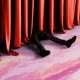 Legs are seen next to a red curtain