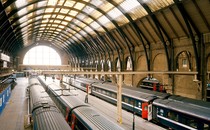 A picture showing the platform of King's Cross train station, in London, daylight radiating from one of the windows.