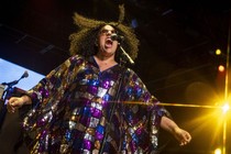A performer sings onstage, their mouth open wide.