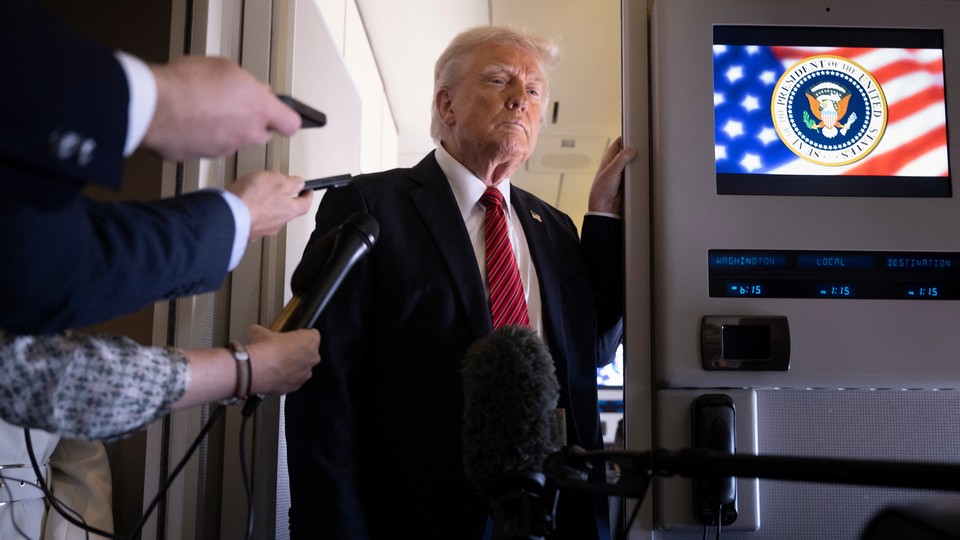 Donald Trump stands next to group of reporters with their arms outstretched.