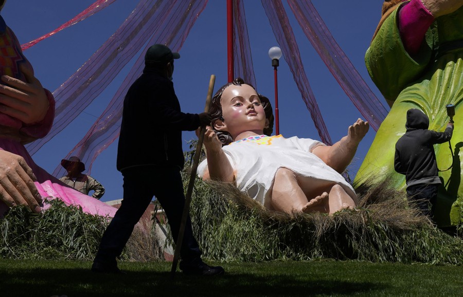 People work on giant statues of Jesus, Mary, and Joseph.