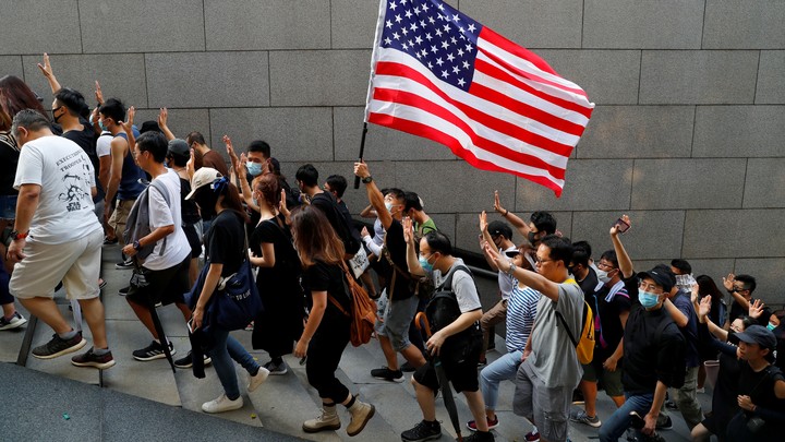 Hong Kong protesters hold up five fingers and brandish an American flag during a march.