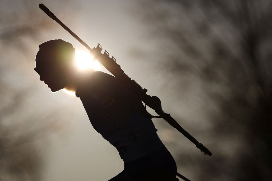 The silhouette of a skier with a rifle slung across his back