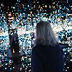 A woman alone in an art installation with hundreds of tiny lights and mirrored walls.