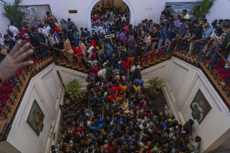 Hundreds of people jam into a room and double staircase in a presidential residence.