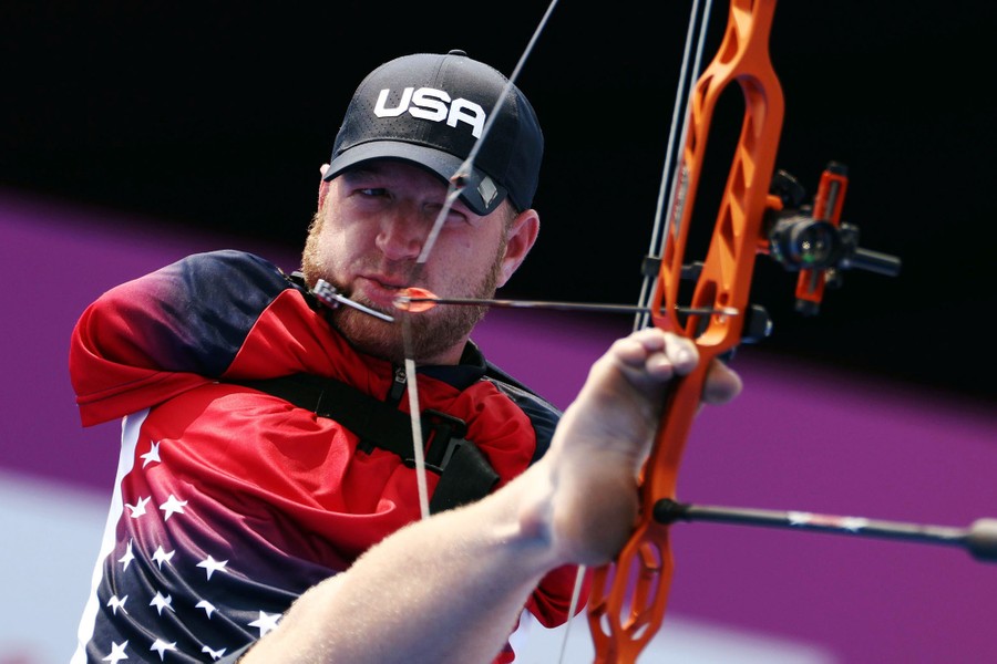 An archer lines up a shot holding his bow with his foot.