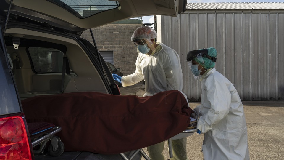 Medical staff push a stretcher with a deceased patient into a car outside of a COVID-19 intensive-care unit in Houston, Texas.
