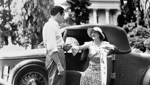 Black-and-white photo of a man helping a woman out of a car