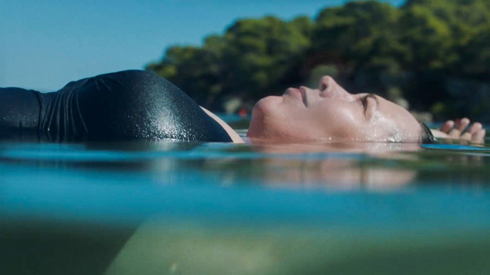 Olivia Colman lying on her back half submerged in the ocean