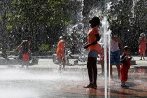 A girl plays near a water fountain on a summer day. 