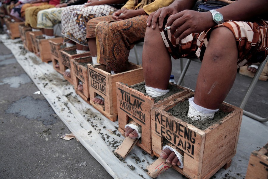 Villagers whose feet are cast in cement blocks sit on a chair as part of four days of protest to draw attention to what they say is environmental damage to their farmland from a cement factory, in Rembang, Central Java, outside the presidential palace in Jakarta, Indonesia, on March 16, 2017.