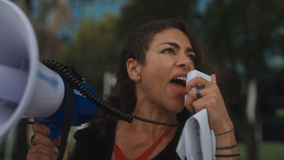 Maryam Henein at a protest, yelling into a megaphone