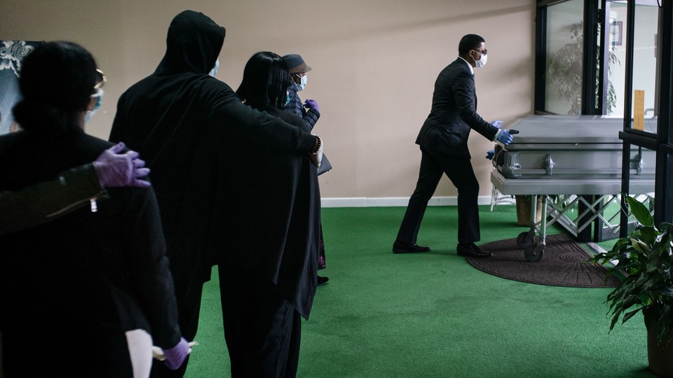 A funeral procession in New Jersey. A black man wearing a mask is pushing a casket.