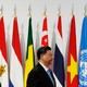 Xi Jinping stands in profile in front of international flags at a meeting of the G20 in 2019.