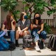 High-school students wearing masks sit together outside a school building.