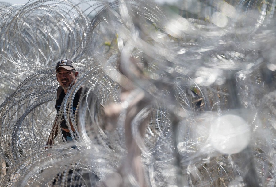 A person walks among many stretched-out coils of razor wire.