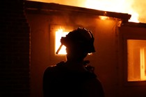 A firefighter monitors a burning structure while battling the Clayton Fire at Lower Lake in California.