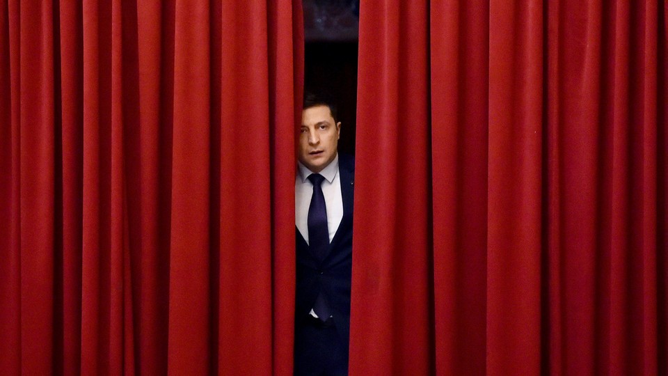 Volodymyr Zelensky as the fictional president of Ukraine, peeking out from behind red curtains, in "Servant of the People"