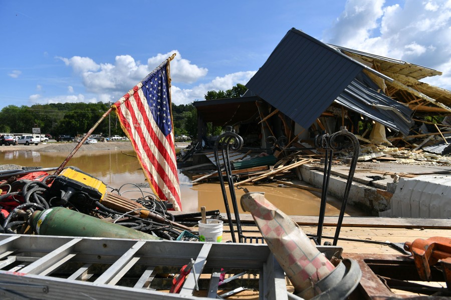An American flag hangs from a stick near a building destroyed by the flooding.
