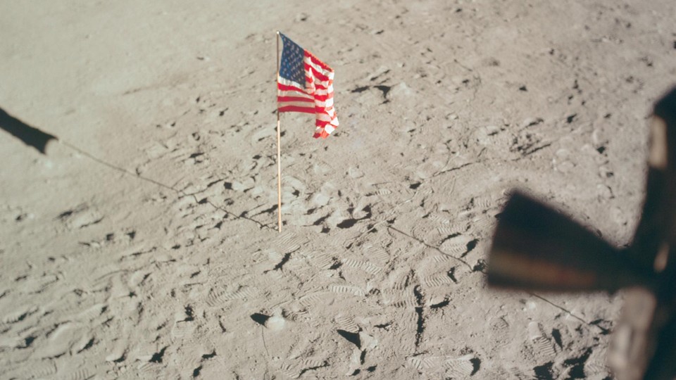 The American flag stands upright on the surface of the moon.