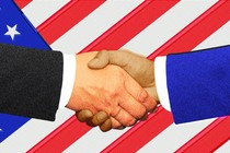 An illustration of shaking hands against a backdrop of the U.S. flag