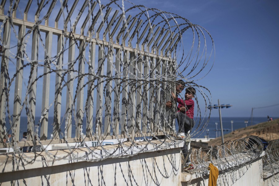 A man helps a boy climb a fence.