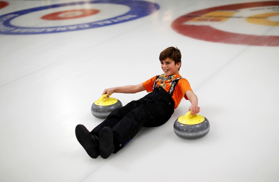 A Yazidi refugee from Kurdistan laughs as he learns the sport of curling at the Royal Canadian Curling Club during an event put on by the "Together Project" in Toronto on March 15, 2017.