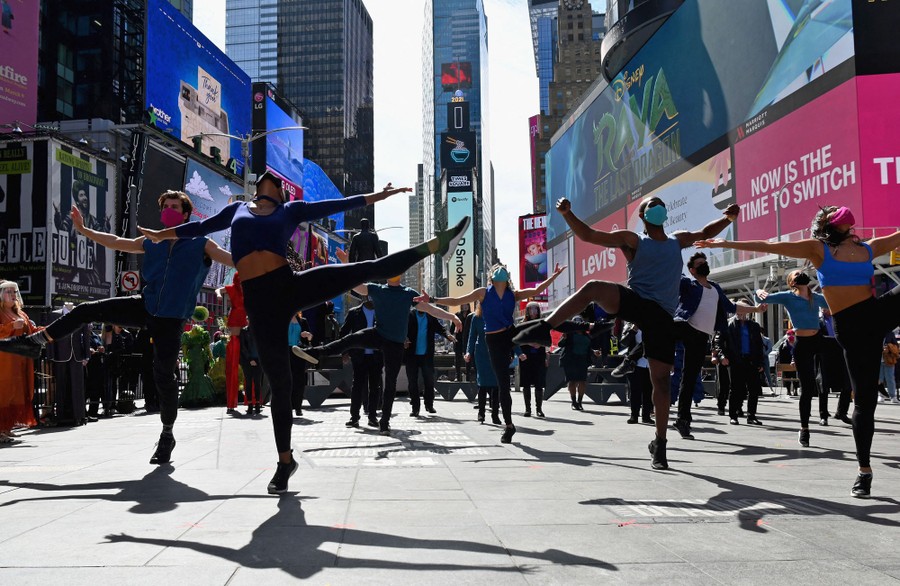 People in masks dance together in the middle of Times Square.