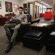 A man sits in a leather chair reading a textbook.