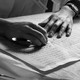 Black-and-white image of a pair of hands on top of a manuscript