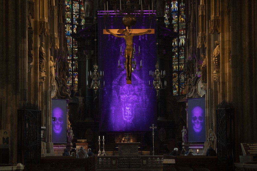 Images of skulls are projected on screens inside a cathedral.