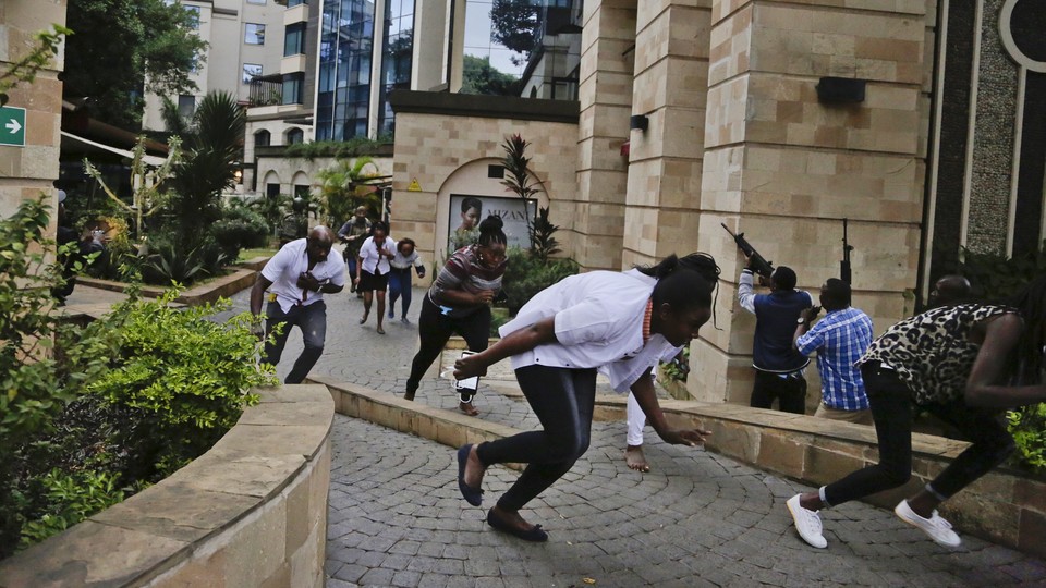 Civilians run with their heads down from the Nairobi hotel complex where terrorists killed at least 14 people on Tuesday.
