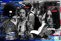 A woman wearing headphones fans herself while waiting for a train on the London underground in July 2015. 