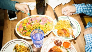 An overhead picture of two people sharing several dishes at a restaurant table