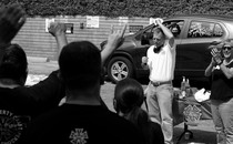 Black and white photo of Mike Miller, vice president of the International Alliance of Theatrical Stage Employees, speaking to members at a rally