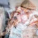 Photo illustration: multiple photographs of bed with mother and baby layered over one another