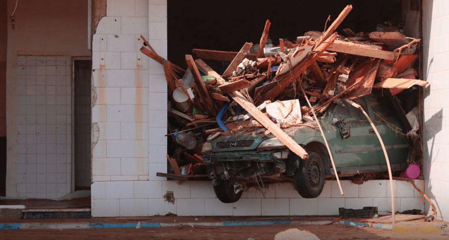 A car and other flood debris sit wedged inside a building.