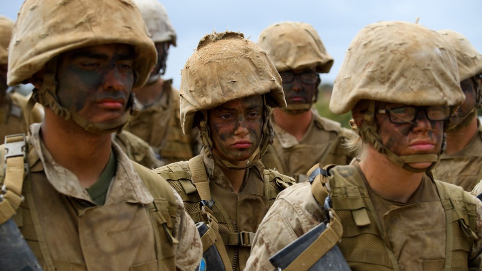 Photo of a female U.S. soldier surrounded by other soldiers in desert-camo uniforms with their faces painted, holding rifles