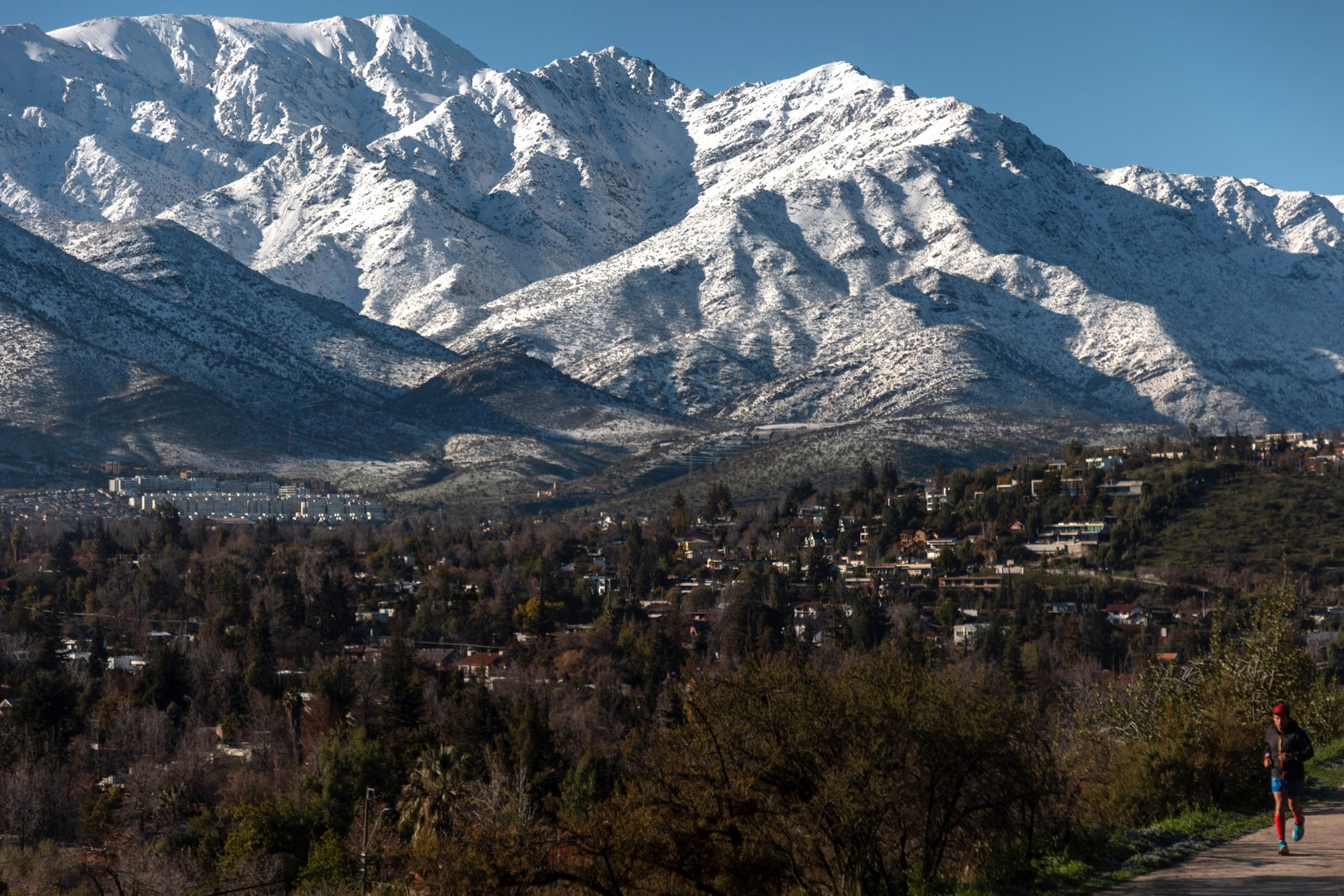 A man jogs with snow-capped mountains in the background.