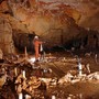 A researcher wearing an orange jumpsuit and a white hard hat in an underground cave
